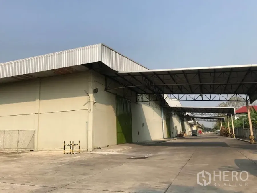 货栈 出租在Bang Pa-in, Phra Nakhon Si Ayutthaya - 仓库立面，多个绿色卷门与连廊雨棚，卡车通道笔直