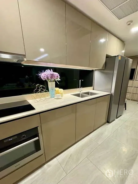คอนโด ให้เช่าในWatthana, Bangkok - ครัวดีไซน์โมเดิร์น ตู้สีเบจ แผงกันเปื้อนสีดำ เตาและเตาอบบิวท์อิน พร้อมตู้เย็นขนาดใหญ่