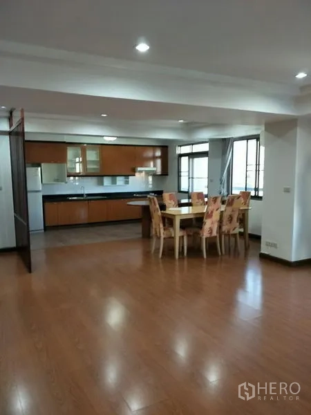 Condominium for rent in Watthana, Bangkok - Spacious living and dining room with recessed lights, six-seat table, and large windows next to the open kitchen.
