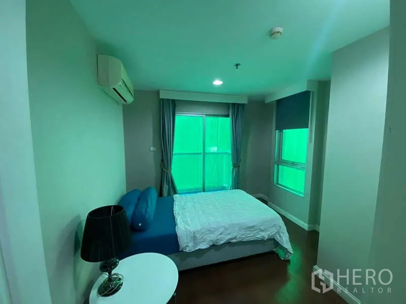 Condominium for  in Huai Khwang, Bangkok - Cozy bedroom with double bed, curtains, air conditioning and corner windows.