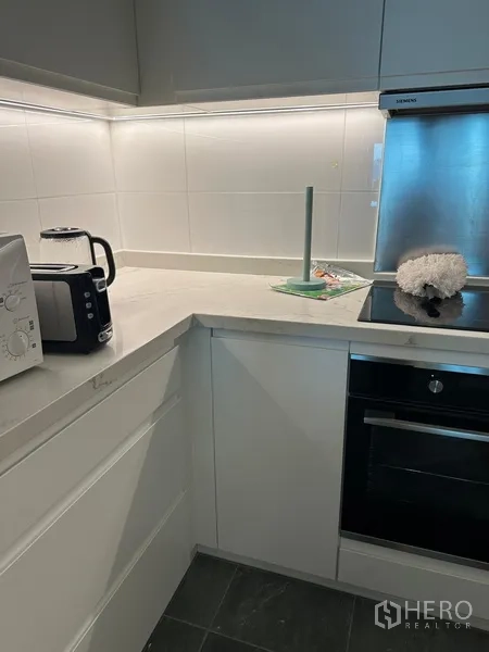 คอนโด ให้เช่าในKhlong Toei, Bangkok - ครัวรูปตัวแอลขนาดกะทัดรัด เคาน์เตอร์ควอตซ์ เตาอบ และเครื่องใช้ไฟฟ้า