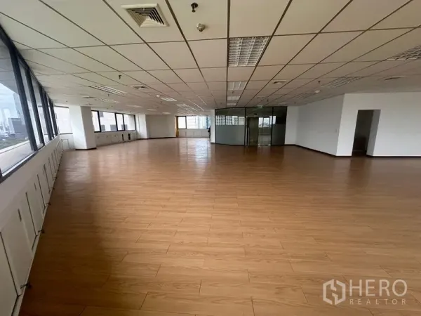 办公空间 出租在Bang Rak, Bangkok - 开阔开间办公室，木纹地板、格栅吊顶照明与城市景观窗。