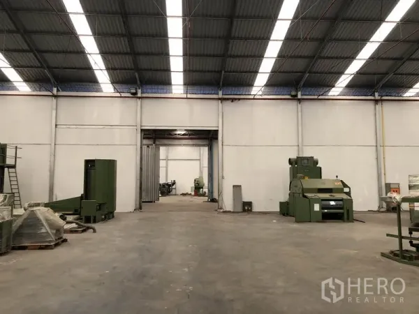 Warehouse for rent in Bang Bua Thong, Nonthaburi - Spacious factory-style interior with skylights and industrial machines on concrete floor.