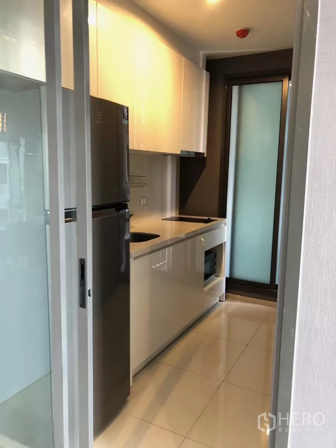 Condominium for rent in Khlong Toei, Bangkok - Galley kitchen with full-size refrigerator, induction cooktop and built-in oven.