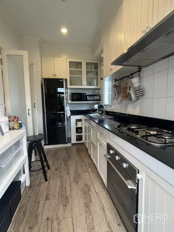 บ้าน ขายในMin Buri, Bangkok - ครัวรูปแกลเลอรี ตู้สีขาว เคาน์เตอร์หินสีดำ เตาแก๊ส เตาอบ และตู้เย็น