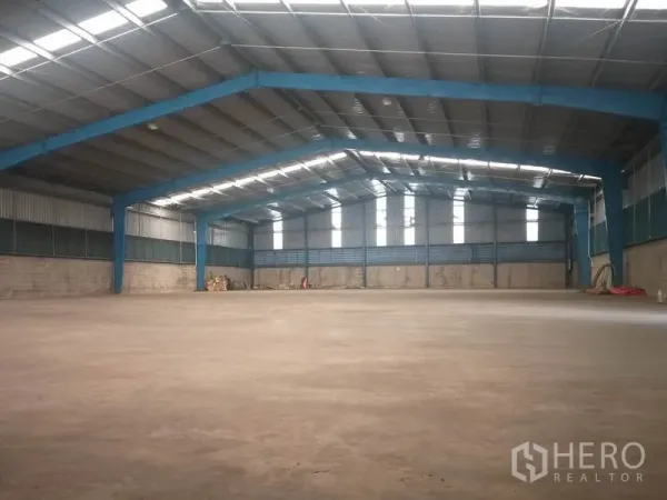 Warehouse for rent in Pathum Thani - Spacious warehouse interior with high steel frame, skylights, and open floor.
