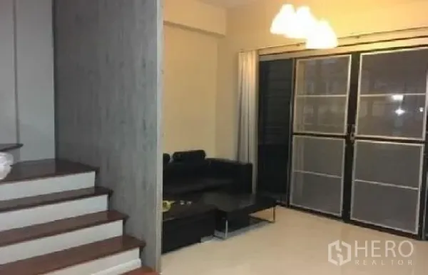 สำนักงานที่บ้าน ให้เช่าในLat Phrao, Bangkok - ห้องนั่งเล่นสว่าง โซฟาสีดำ โคมไฟแขวน ประตูกระจกบานเลื่อน ข้างบันไดไม้