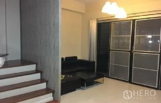 สำนักงานที่บ้าน ให้เช่าในLat Phrao, Bangkok - ห้องนั่งเล่นสว่าง โซฟาสีดำ โคมไฟแขวน ประตูกระจกบานเลื่อน ข้างบันไดไม้