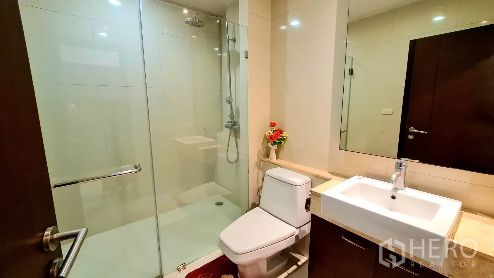 อพาร์ทเมนท์ ให้เช่าในWatthana, Bangkok - ห้องน้ำอีกหนึ่งห้องพร้อมตู้กระจกกั้นอาบน้ำ อ่างล้างหน้า โถสุขภัณฑ์ และผนังโทนอบอุ่น