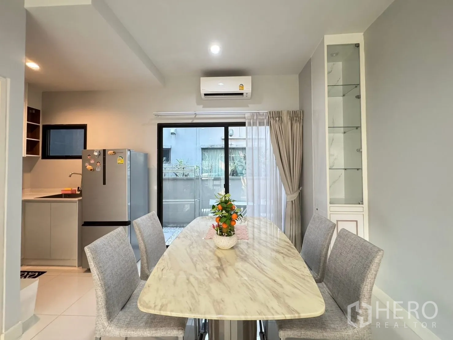 Townhouse for rent in Saphan Sung, Bangkok - Dining area with marble-top table, four chairs and sliding glass door.