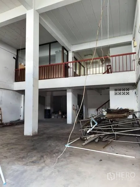 Shophouse for sale in Pathum Thani - High-ceiling workspace with red-railed mezzanine and support columns.