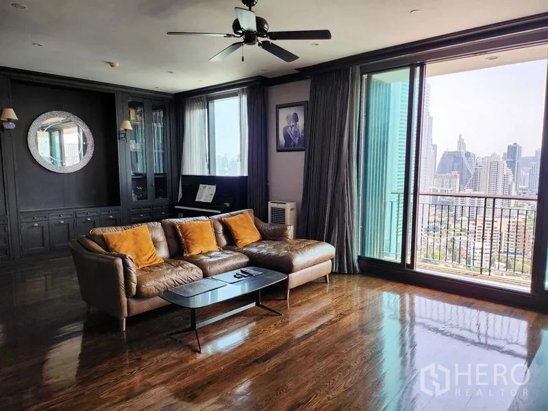 Condominium for sale in Khlong Toei, Bangkok - Sofa seating beside floor-to-ceiling windows and balcony access with city view.