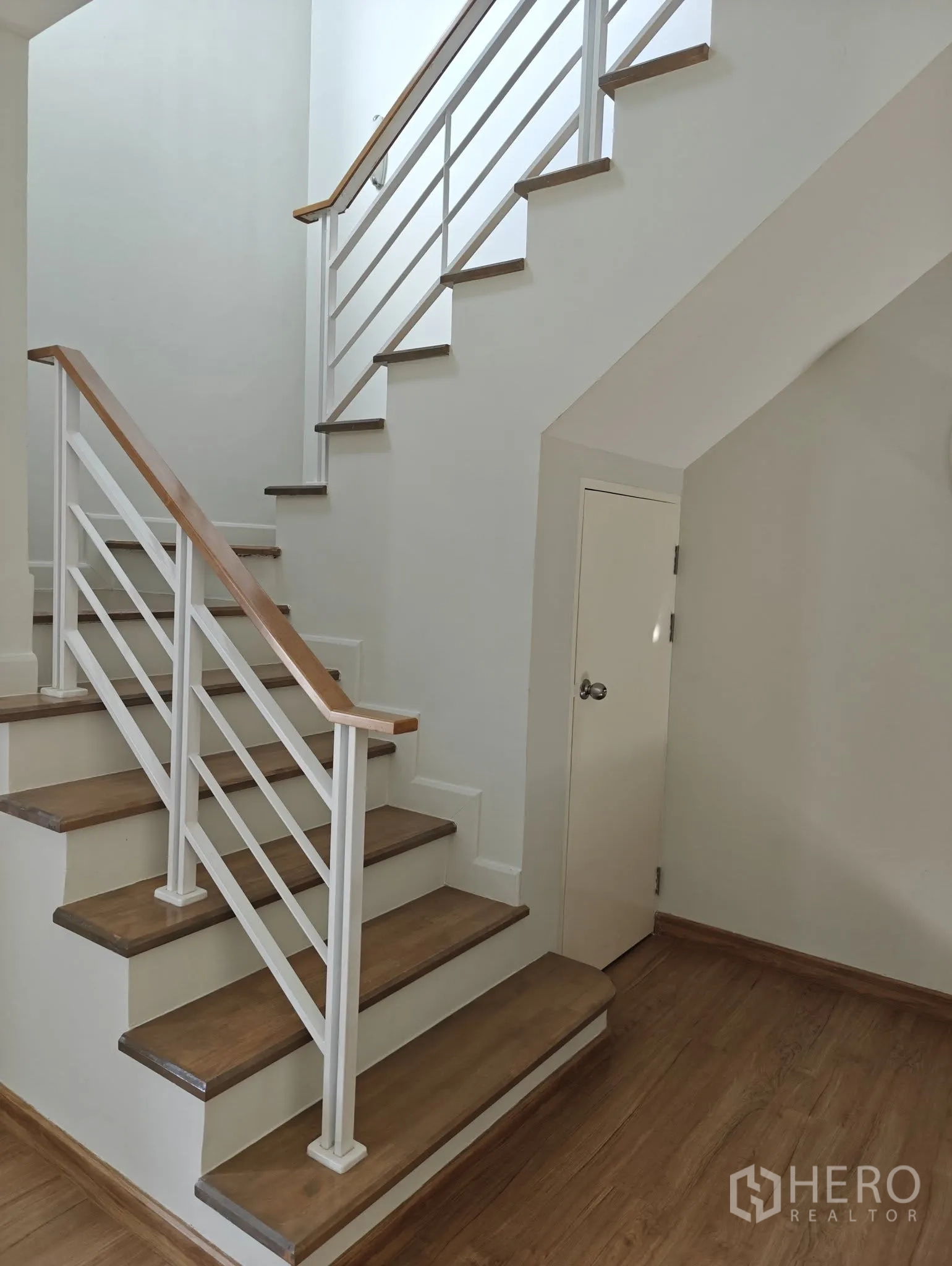 联排别墅 出租或出售在Lat Phrao, Bangkok - 木踏步楼梯配白色扶手，楼梯下方设储物柜。