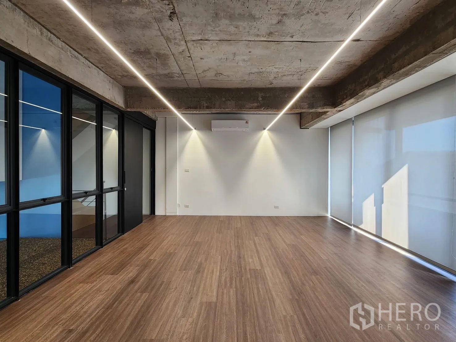 家庭办公室 for rent in Chatuchak, Bangkok - 开放式办公区，木纹地板、裸露混凝土天花、线性灯和玻璃隔断。