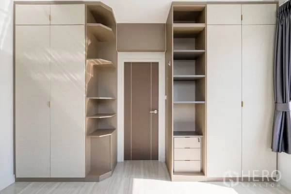 Home Office for rent in Khlong Toei, Bangkok - Built-in wardrobes with open shelving and storage in a sunlit room.