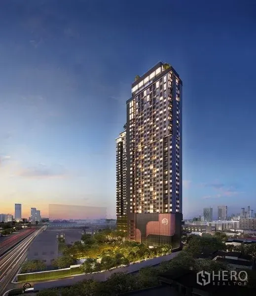 Condominium for sale in Khlong Toei, Bangkok - Twilight exterior of a high-rise condominium tower with city skyline and nearby rail line.
