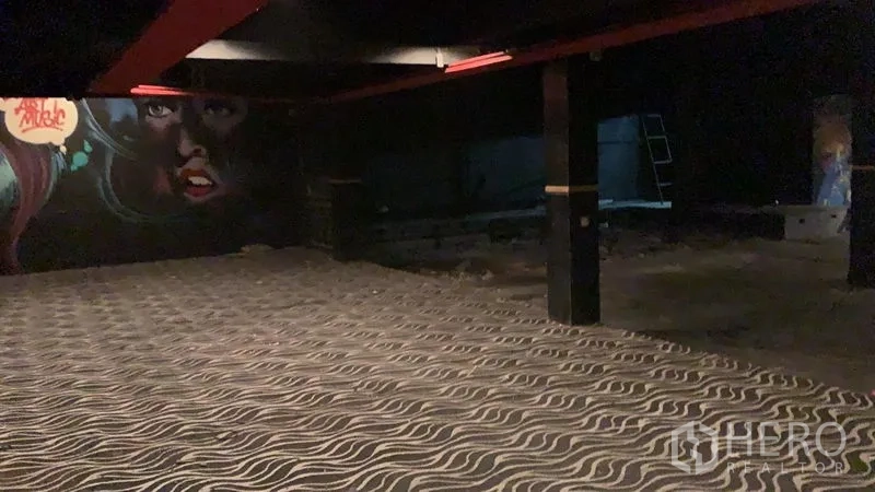 店屋 出租在Watthana, Bangkok - 宽敞的深色室内，波浪纹地毯、黑色立柱与大型涂鸦墙面。