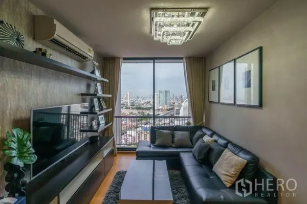 公寓 出租或出售在Bang Rak, Bangkok - 客厅设影音墙与水晶吊灯，阳台门框出曼谷市中心景观。