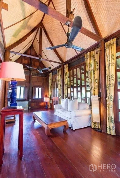 บ้าน ให้เช่าในBang Na, Bangkok - ห้องนั่งเล่นเพดานสูง โชว์คานไม้ พัดลมเพดาน พื้นไม้ และโซฟา