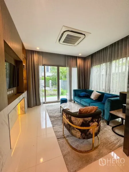 Detached House for rent or sale in Bueng Kum, Bangkok - Bright living room with teal sofa, floor-to-ceiling windows and view to the front garden.
