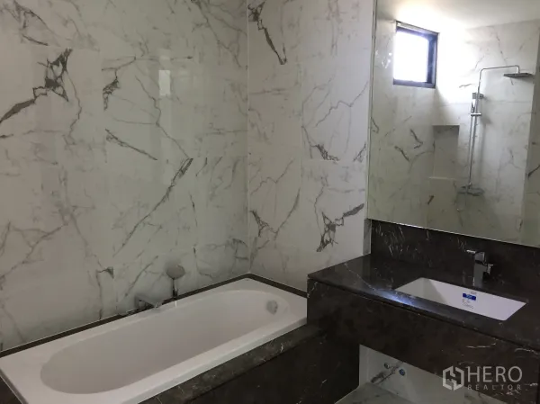 Townhouse for rent in Saphan Sung, Bangkok - Marble-tiled bathroom featuring a bathtub, vanity and separate shower area.