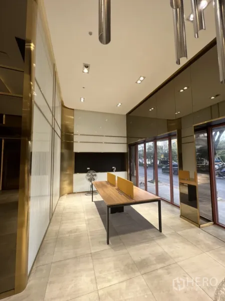 店屋 出租在Phra Khanong, Bangkok - 临街一层零售区，落地窗、瓷砖地面与长工作台，射灯明亮。