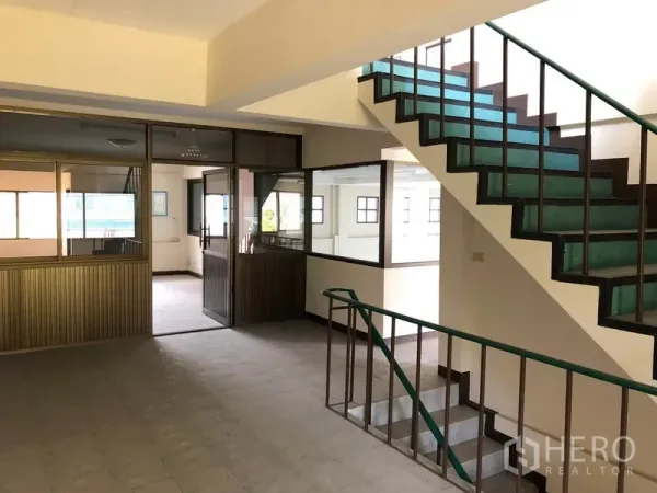 Shophouse for sale in Lam Luk Ka, Pathum Thani - Internal staircase beside glass-partitioned office rooms on the mezzanine.