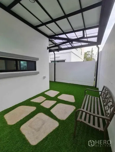 ทาวน์เฮาส์ ให้เช่าในBang Phli, Samut Prakan - มุมระเบียง/ลานพักผ่อนมีหลังคา ม้านั่งและแผ่นทางเดินบนหญ้าเทียม ข้างทาวน์เฮ้าส์