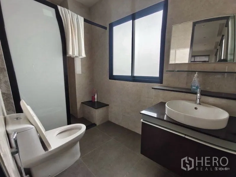 Shophouse for rent or sale in Pom Prap Sattru Phai, Bangkok - Modern bathroom with glass shower screen, vanity, and window for natural light.