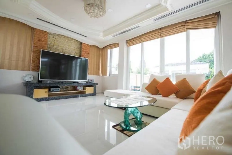 Detached House for rent or sale in Bang Kapi, Bangkok - Modern living room with L-shaped sofa, large TV and floor-to-ceiling windows.