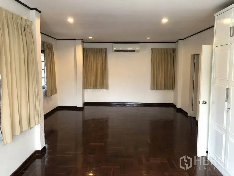 Detached House for rent - Large master bedroom with polished wood floors and wall-mounted air conditioner.