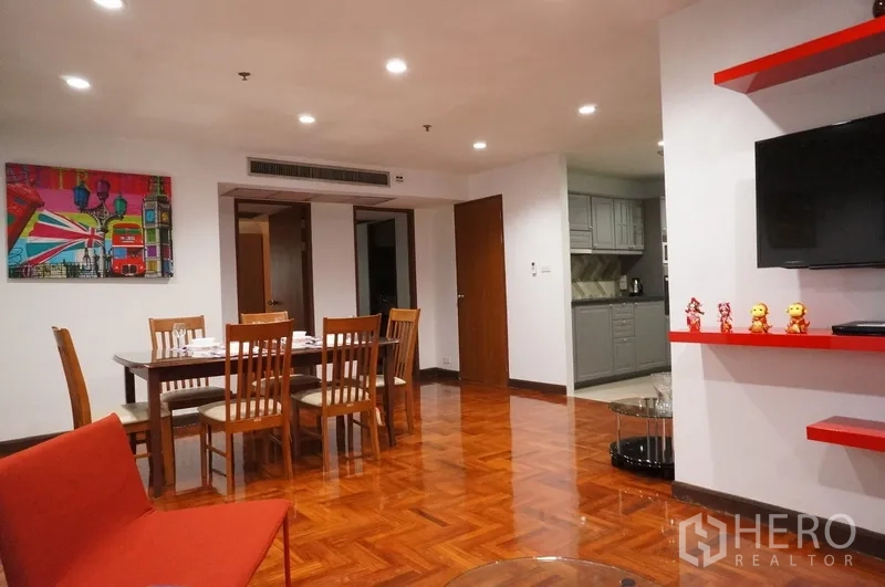 Condominium for rent in Watthana, Bangkok - Open-plan dining for six beside colorful artwork, recessed lighting and access to the gray kitchen.