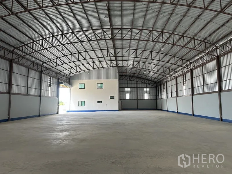 工厂 出租或出售在Sai Noi, Nonthaburi - 仓库内部，高挑拱形钢结构屋顶与抛光混凝土地面。