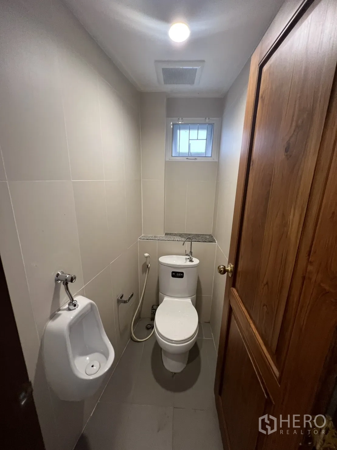 Shophouse for rent in Samphanthawong, Bangkok - Compact restroom with toilet, urinal, bidet spray and a small ventilating window.
