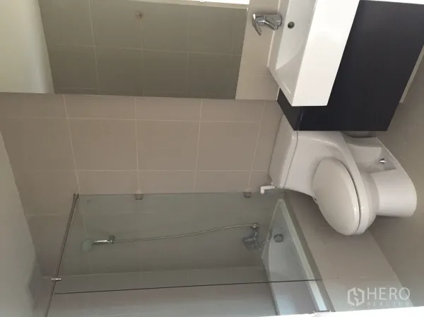 Condominium for rent in Khlong Toei, Bangkok - Tiled bathroom featuring bathtub with glass screen, vanity and toilet.