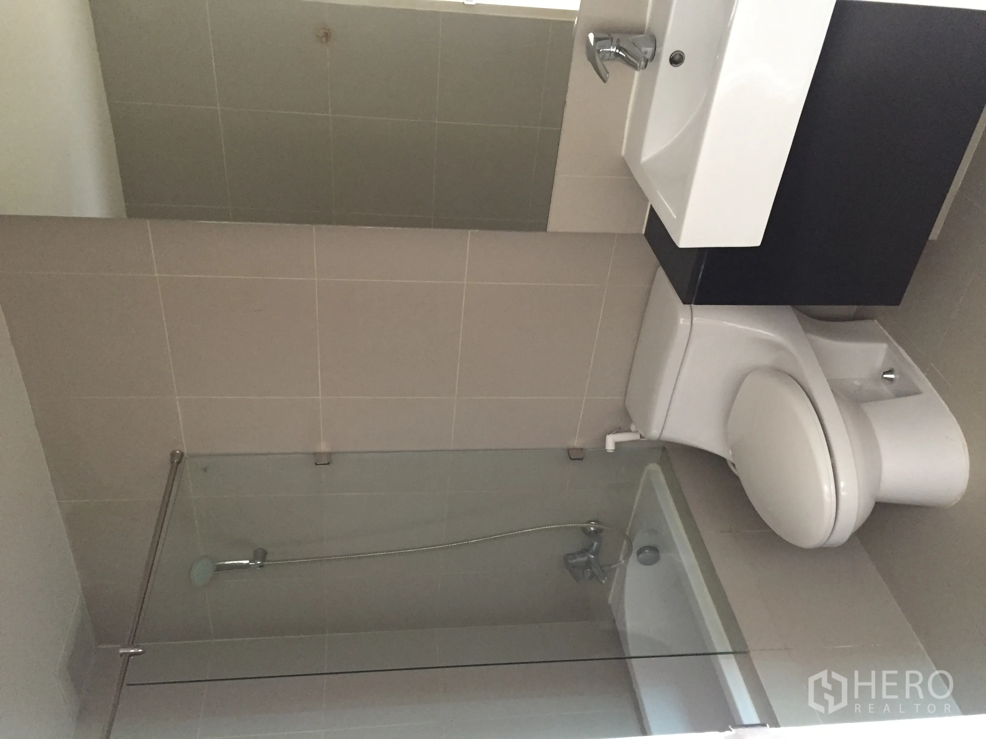 Condominium for rent in Khlong Toei, Bangkok - Tiled bathroom featuring bathtub with glass screen, vanity and toilet.