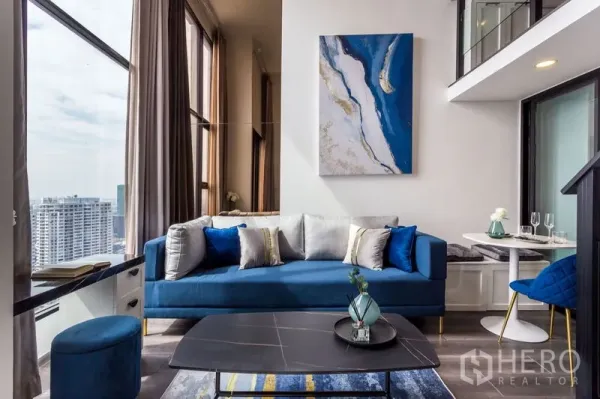 公寓 出租或出售在Chatuchak, Bangkok - 蓝色沙发的客厅，超高窗户与城市景观，旁有用餐角