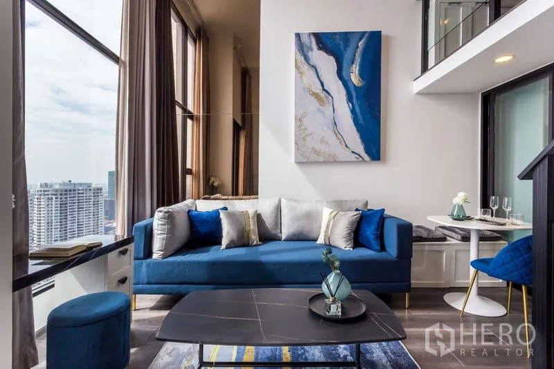 公寓 出租或出售在Chatuchak, Bangkok - 蓝色沙发的客厅，超高窗户与城市景观，旁有用餐角