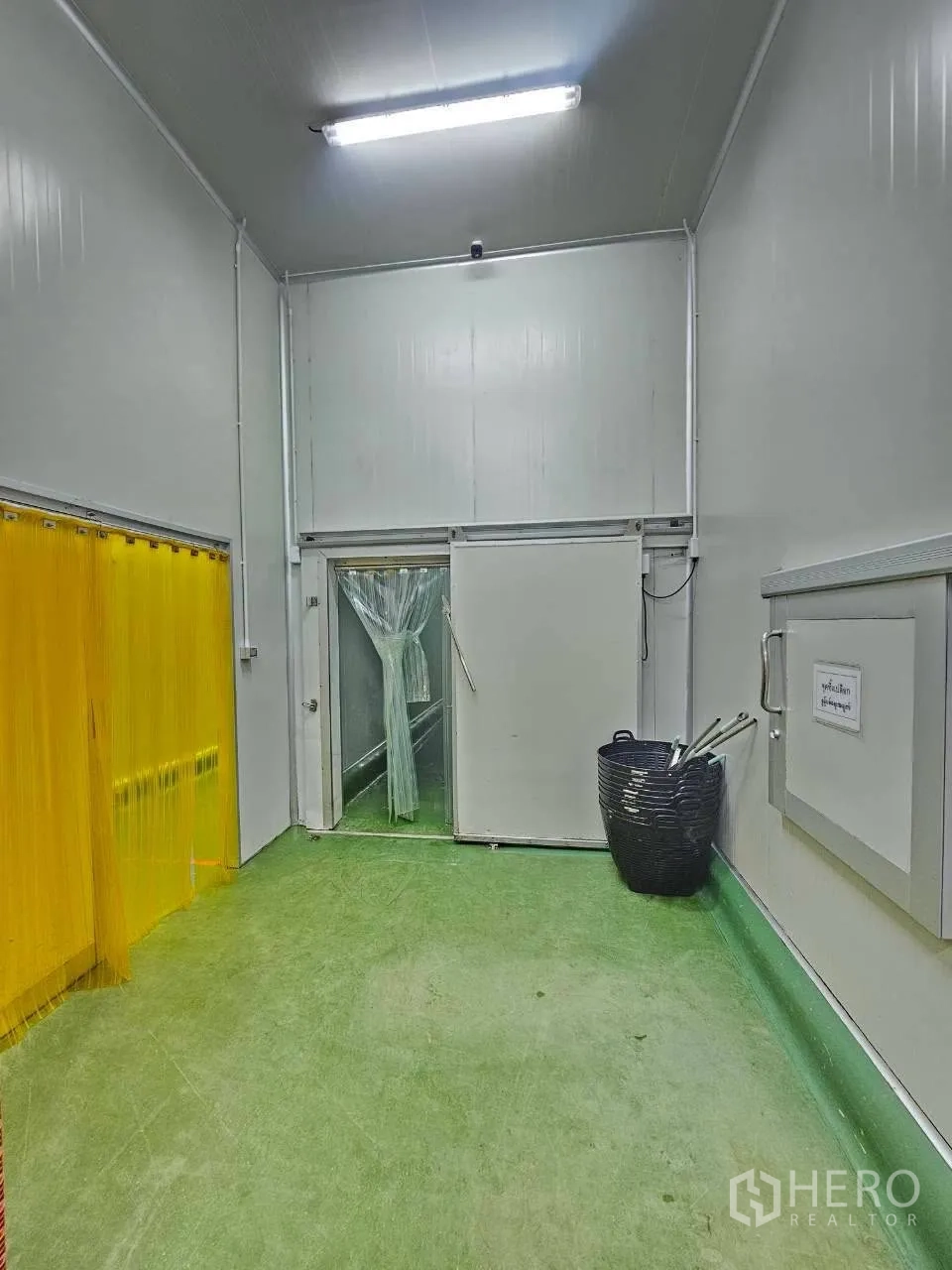 工厂 for rent in Mueang Samut Sakhon, Samut Sakhon - 入口区，绿色地面与双处塑料软帘门。