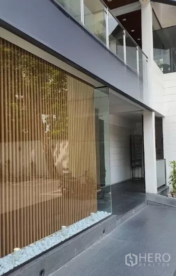 零售空间 出租在Watthana, Bangkok - 店面侧视，落地玻璃、木百叶与白色装饰碎石