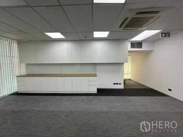 Office Space for rent - Open-plan office with carpet tiles, ceiling lights, and long storage cabinets.