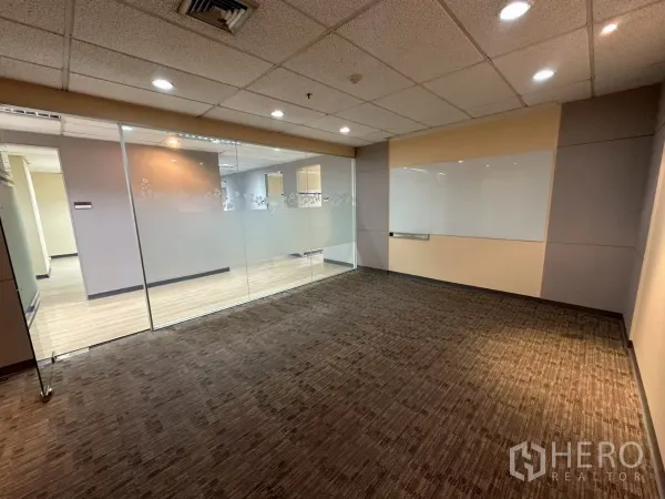 Office Space for rent in Watthana, Bangkok - Meeting room with carpet, glass partition and wall whiteboard under spotlights.