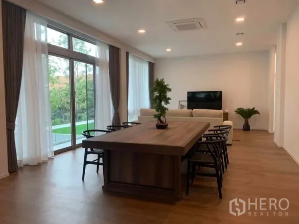 บ้าน ให้เช่าในSaphan Sung, Bangkok - ห้องนั่งเล่น–ทานอาหารกว้าง พื้นไม้ หน้าต่างสูงจรดเพดาน ผ้าม่านโปร่ง พร้อมโซฟาและทีวี