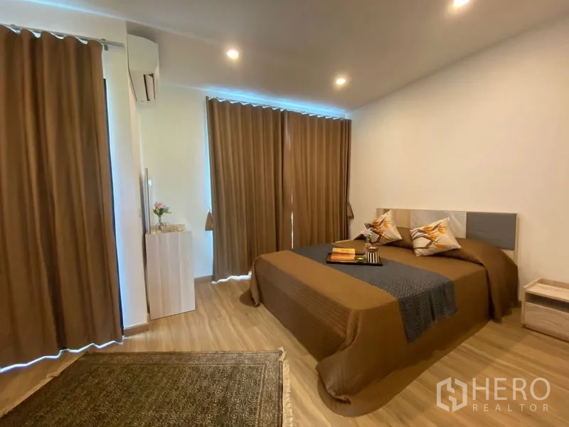 Townhouse for rent in Bang Kapi, Bangkok - Cozy bedroom with double bed, dark curtains, recessed lights, and wood flooring.
