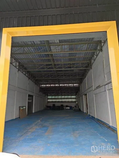 Warehouse for rent in Bang Phli, Samut Prakan - Deep warehouse bay framed by a yellow portal and steel truss roof.