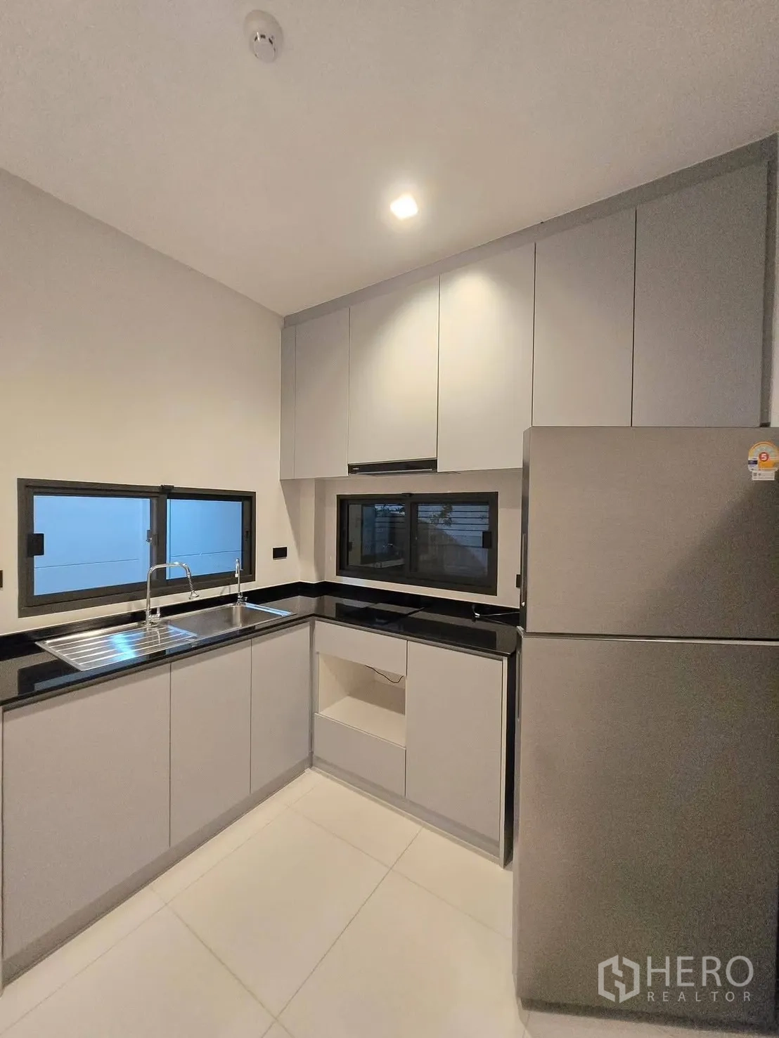 บ้าน for rent or sale in Bang Phli, Samut Prakan - ครัวรูปตัว U ตู้สีเทา เคาน์เตอร์หินสีดำ และหน้าต่างสองบาน