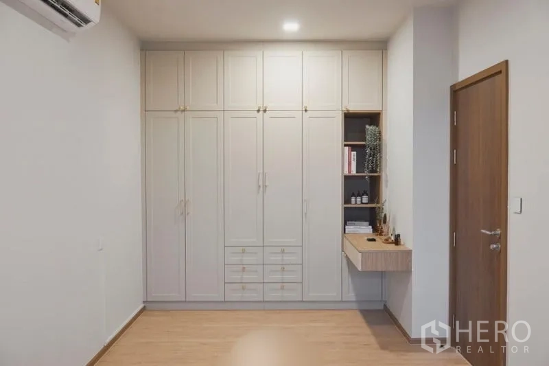 Condominium for sale in Suan Luang, Bangkok - Room with full-height built-in wardrobes and a small dressing nook over wood floors.