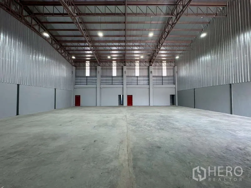 货栈 出租在Bang Phli, Samut Prakan - 仓库内部视角，墙体高窗与红色门