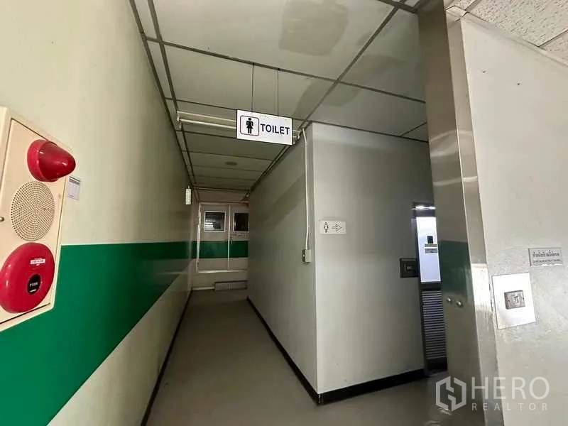 โรงงาน ให้เช่าหรือขายในThanyaburi, Pathum Thani - โถงทางเดินภายใน มีป้ายบอกทางห้องน้ำ แถบสีเขียว และอุปกรณ์ดับเพลิง