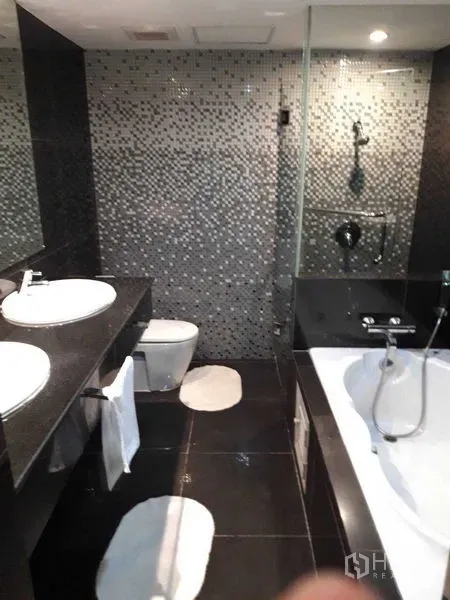 Condominium for sale - Modern bathroom with double vanity, bathtub, and glass shower.